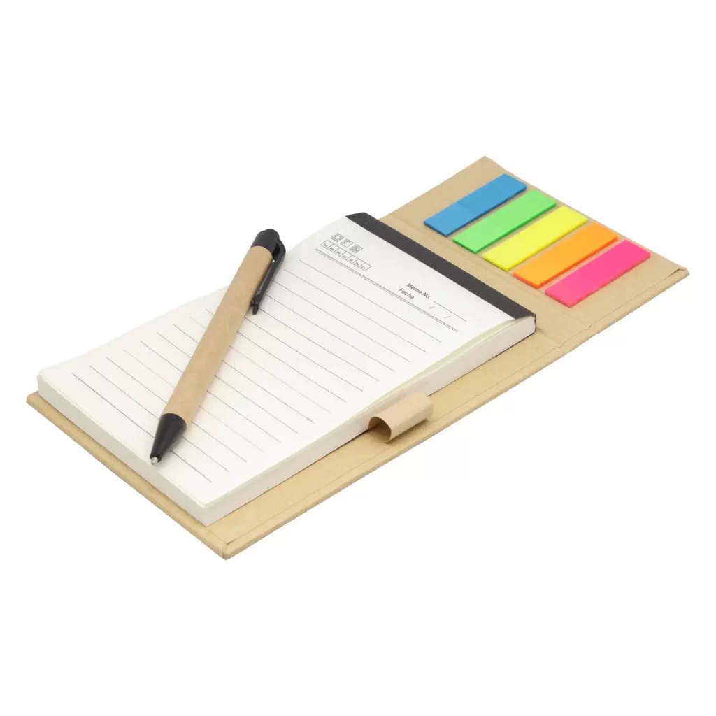 Libreta anotador de cartón kraft abierta con bolígrafo reciclado, bloc de hojas ahuesadas y banderitas señaladoras de colores